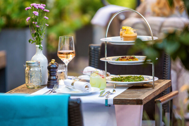 Gedeckter Tisch mit Etagere im Hofgarten des Restaurants alto