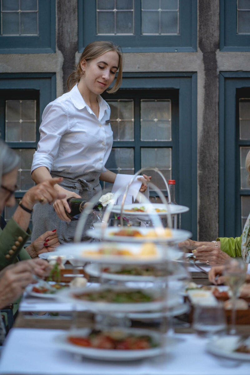 Employee serves guests in the courtyard garden of the restaurant alto